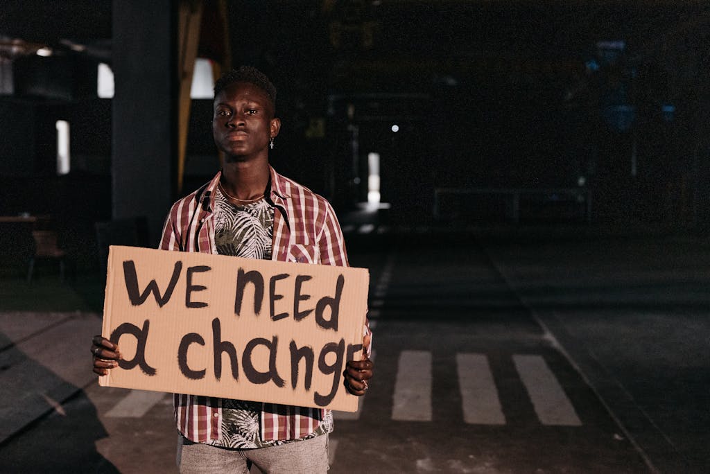 A determined activist holding a sign with a social message in a dimly lit street.